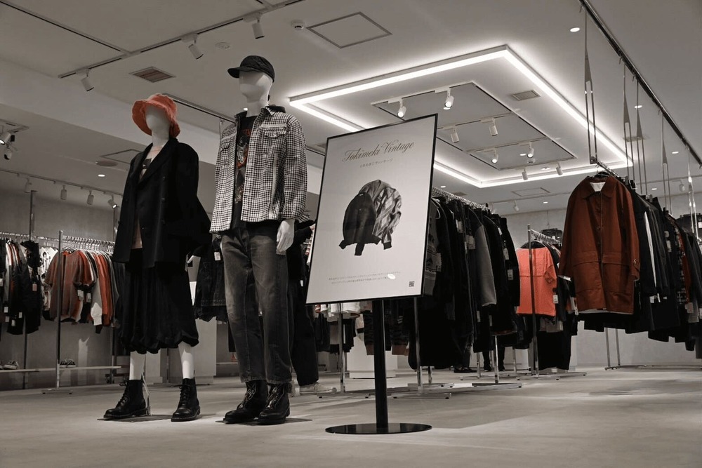 Two styled mannequins displayed beside clothing racks inside the store